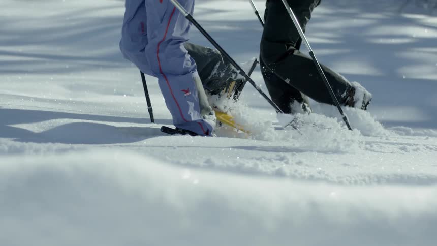 Two people hike through the snow with snowshoes on