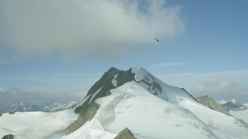 Helicopter flies over snowy mountains