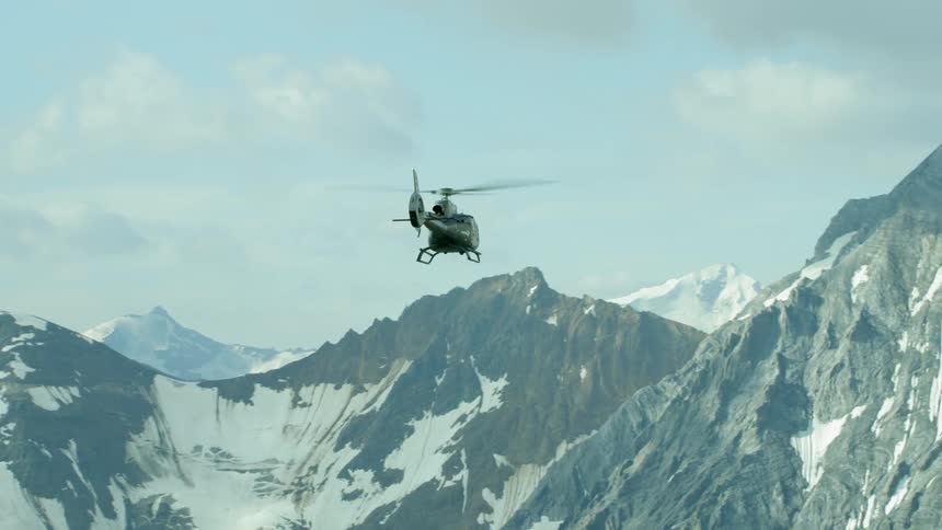 Helicopter flies over snowy mountains