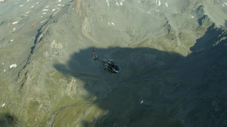 Helicopter flies over mountain range on a sunny day