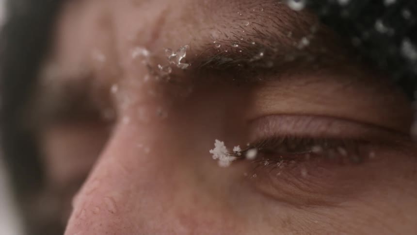 A snowflake bounces off a man's eyeball in slow motion
