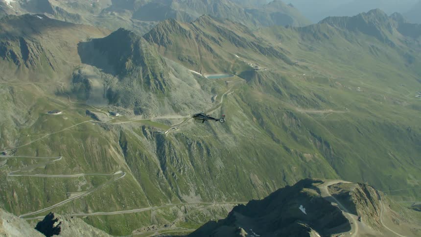 A helicopter flies above mountains