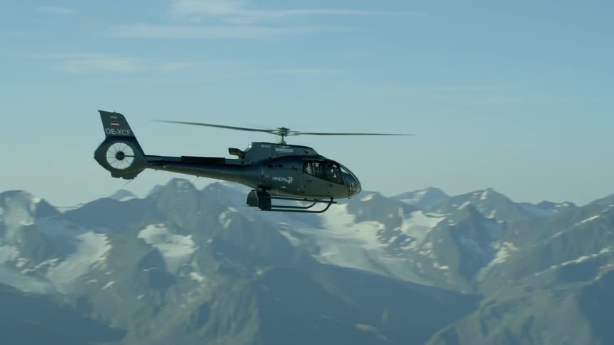 The helicopter is hovering above the snow covered mountains