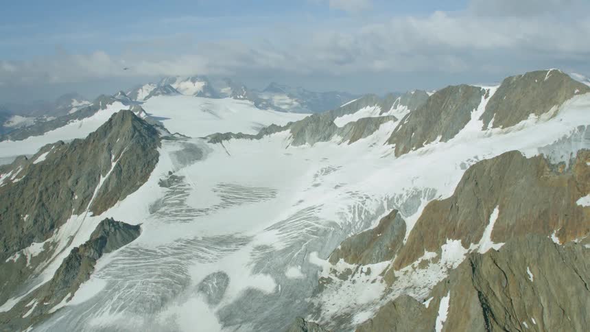 A helicopter flies over snowy mountains