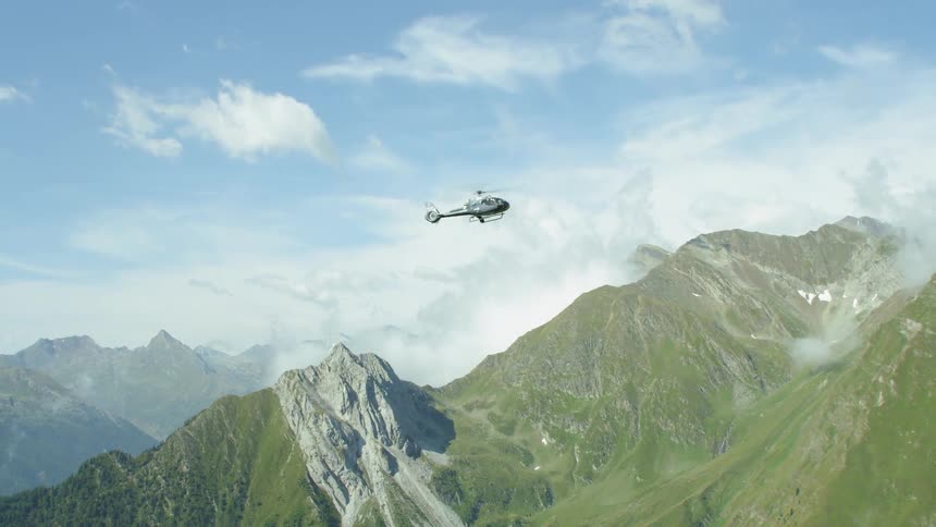 A helicopter flies above mountains