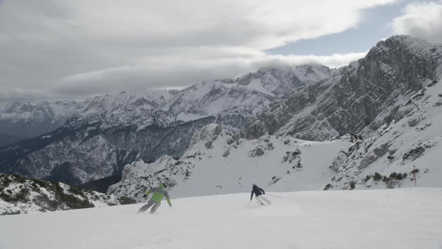 Two skiers descend down the mountain