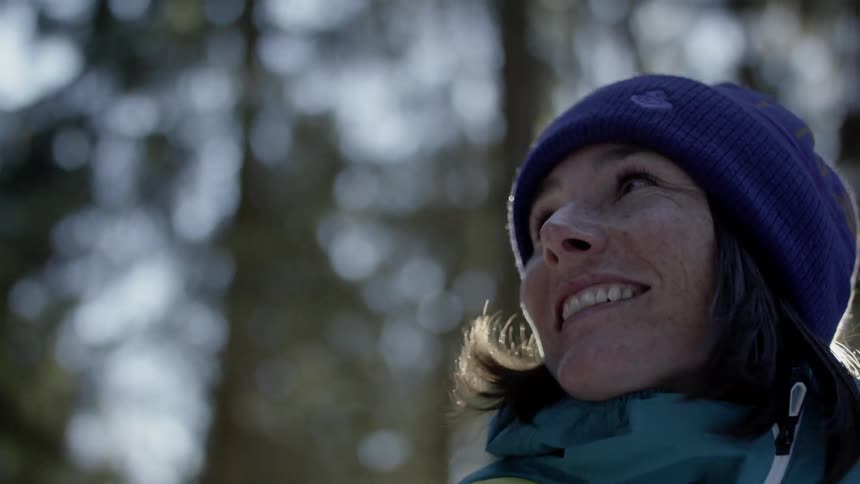 A woman walking in the woods looks back and smiles at her companion