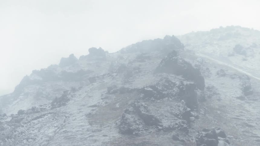 Snow falls rapidly atop a mountain