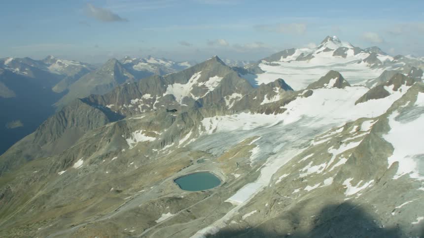 A helicopter flies above mountains
