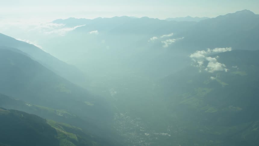 Clouds hang softly above a valley between mountains