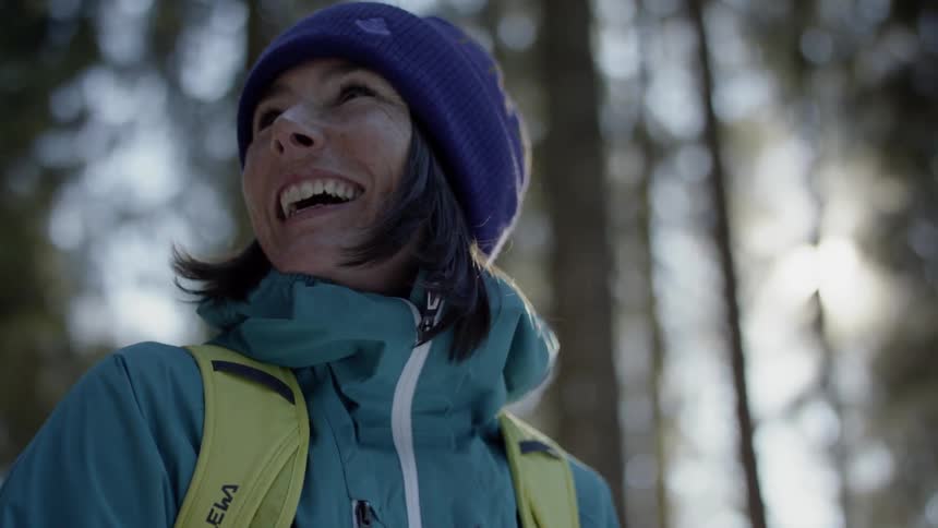 A woman laughs while hiking in a forest
