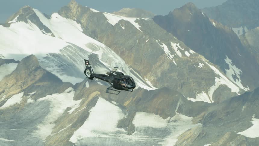 Helicopter hovers over a snowy mountain