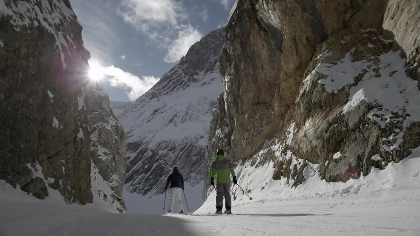 Two people ski down the mountain trail