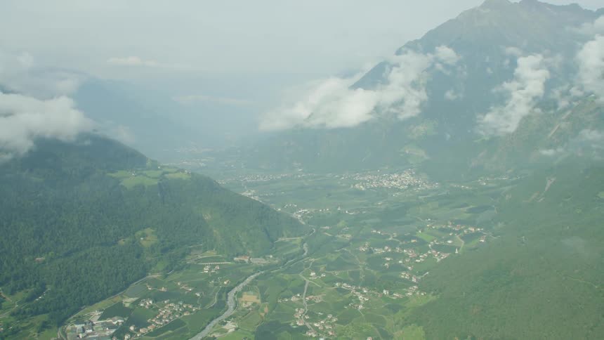 Clouds hover over mountains with houses below