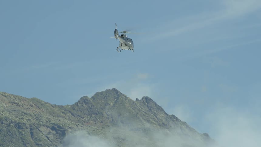 A helicopter flies high above the clouds