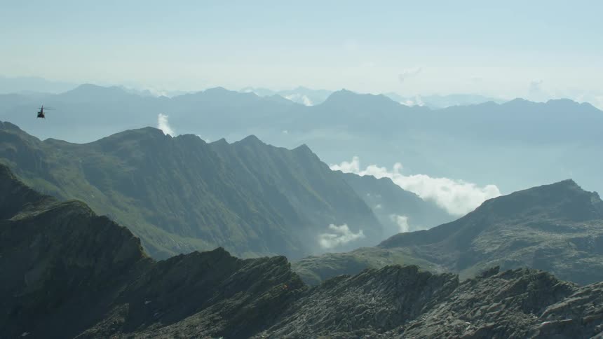 A helicopter flies over mountains