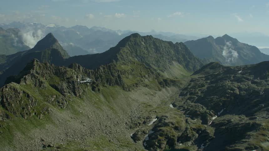 A helicopter is flying above a mountain range in daylight
