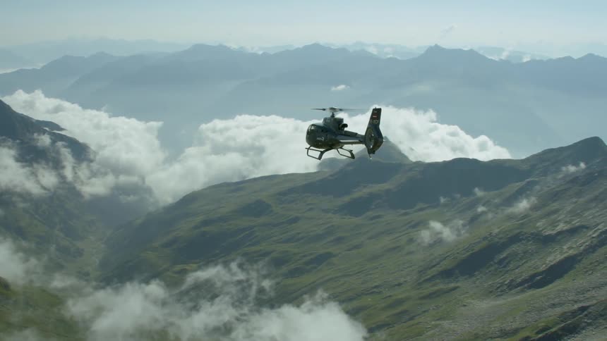 A helicopter flies above mountains