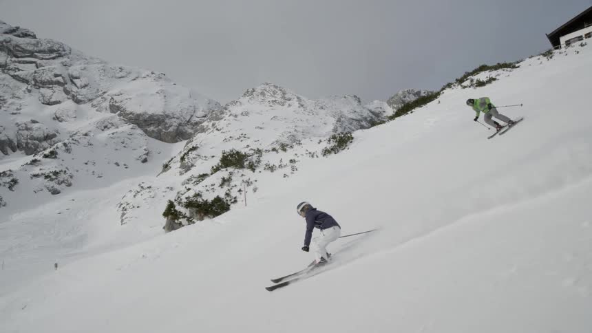 Two skiers descend down the mountain