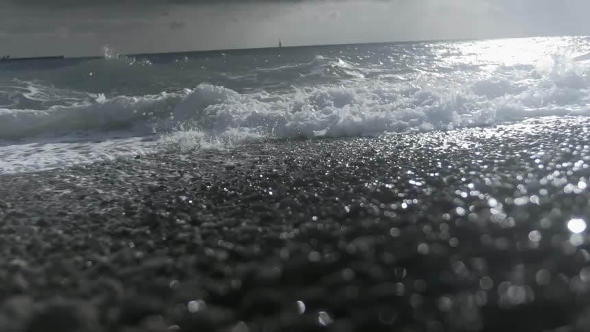 Ocean waves wash ashore a pebbly beach