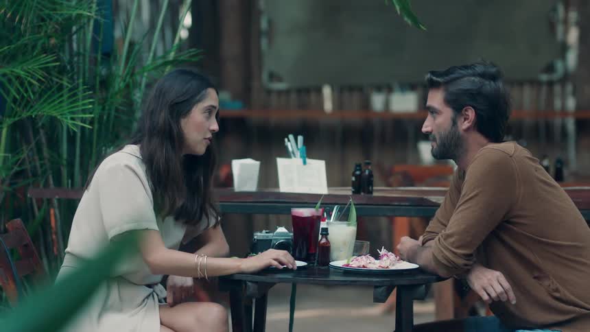 A couple sit at an outdoor restaurant and talk