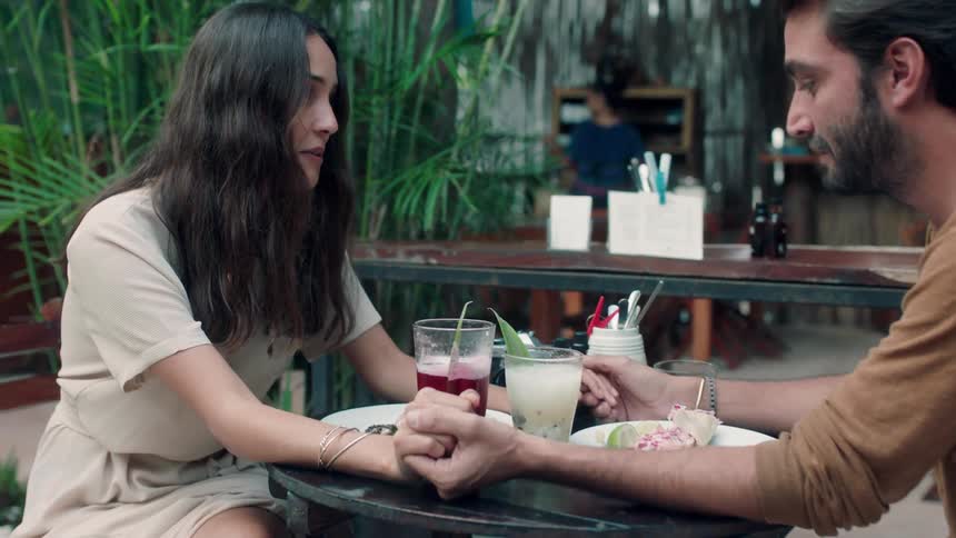 A man and woman hold hands while dining together