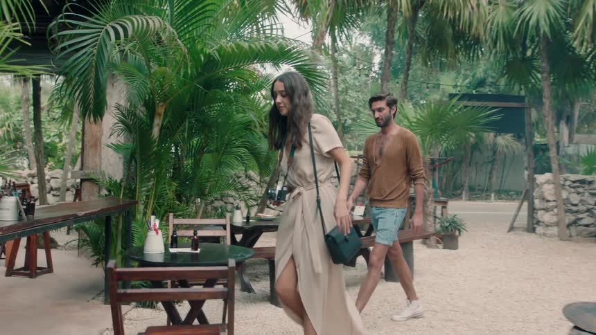 A couple are walking into an outdoor restaurant during the day