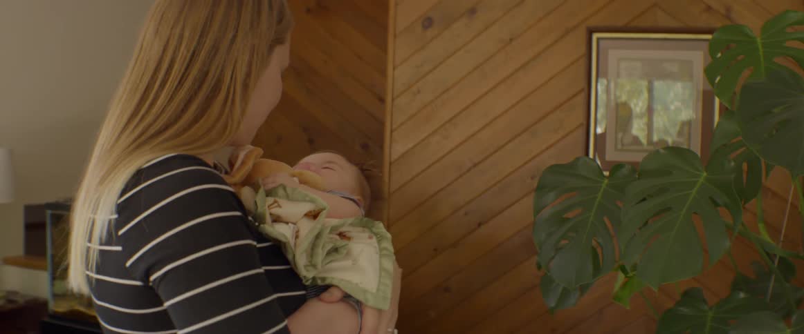 A woman rocks a newborn while standing