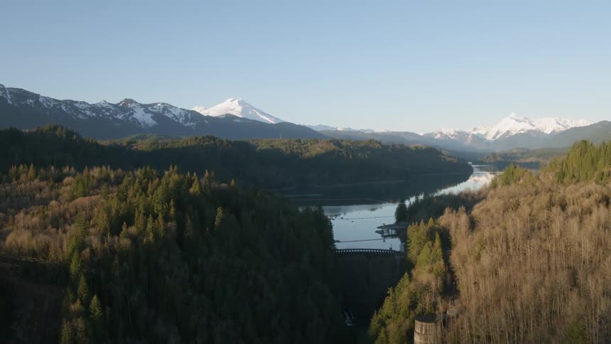 Orbiting around a dam reservoir surrounded by mountains and forest
