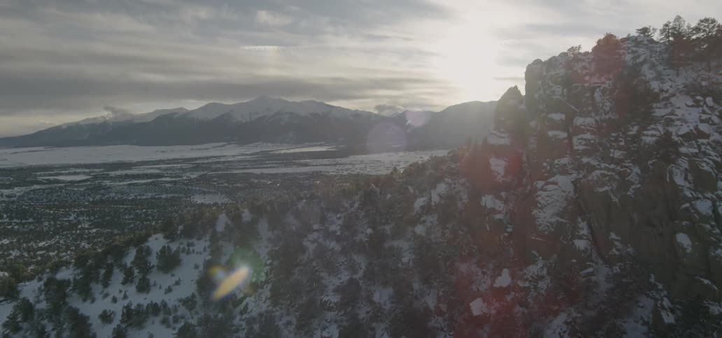 The sun is shining down on a snow-covered mountain valley