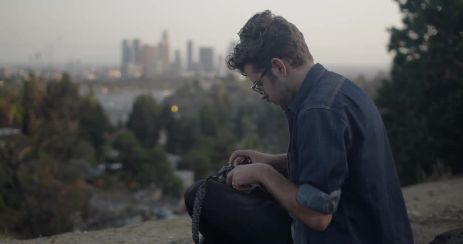 Photographer loads film into his camera overlooking a city