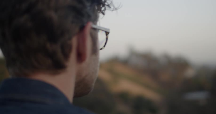 Man stands on a hilltop overlooking a city