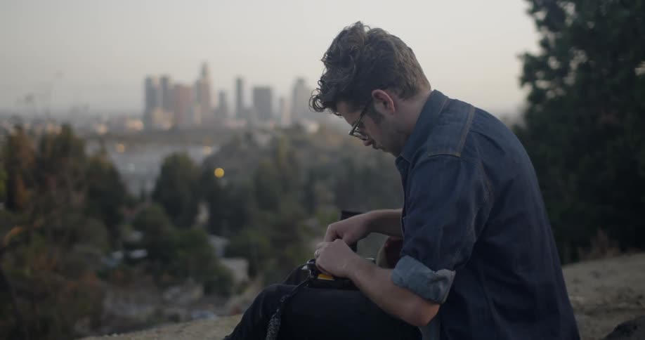 Photographer loads film into his camera at sunset