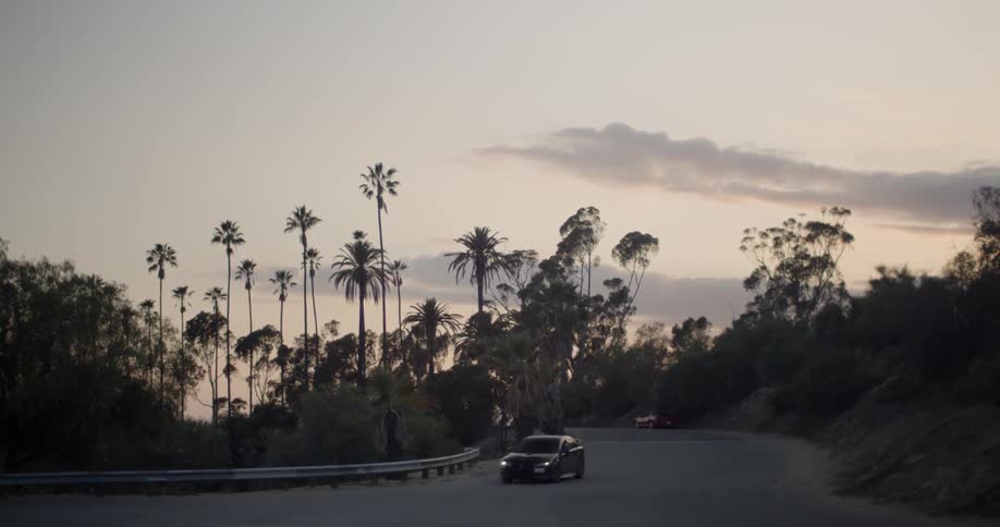 A car drives on a winding road at sunset