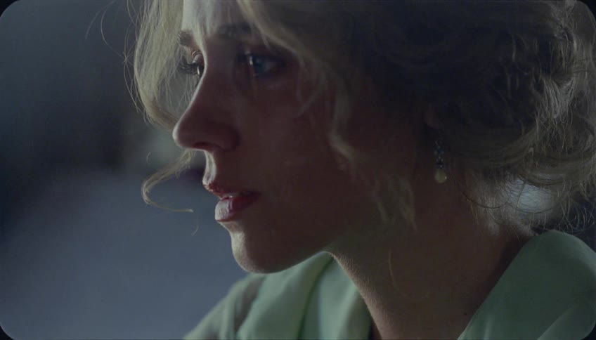 A woman looks forward in a dark room