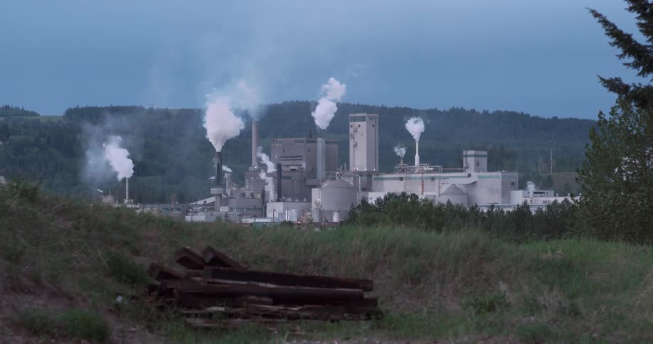 Smoke and steam billow from an industrial plant during the day