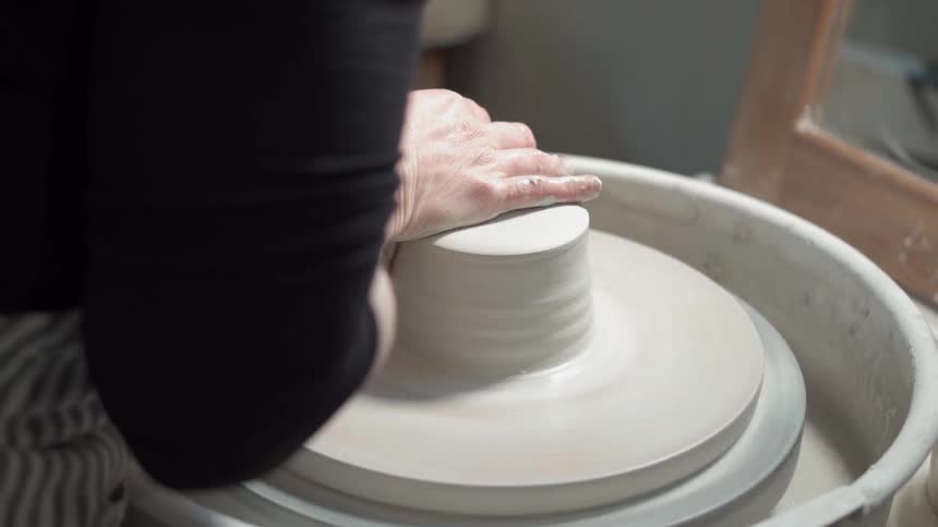 A person is forming clay on a pottery wheel