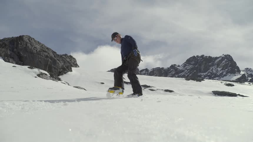 A man is side stepping down an icy slope with ice axe