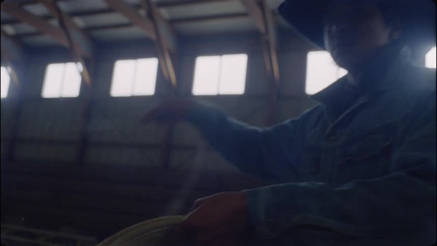 A cowboy swings his lasso in the barn