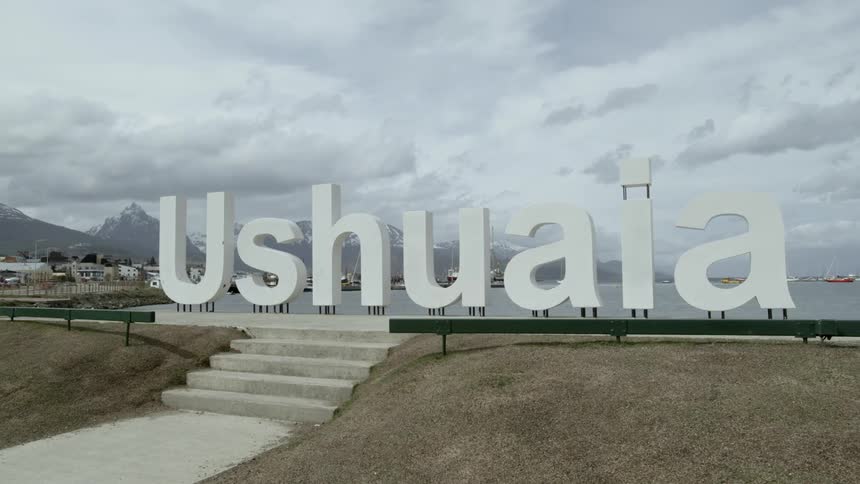 Cars travel by a sign reading ushuaia