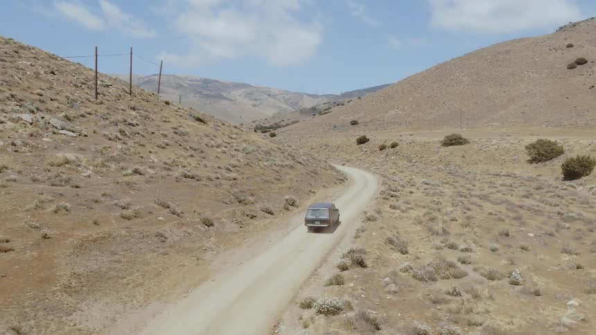 A car drives down the desert trail