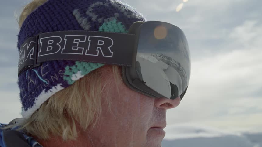 A man looks out over the mountains wearing ski goggles