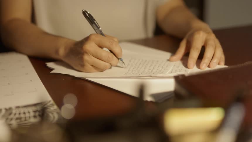 A person is writing a letter at a desk