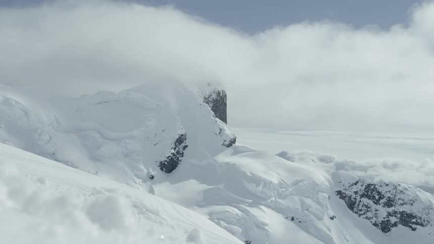Clouds float over snowy mountains in timelapse