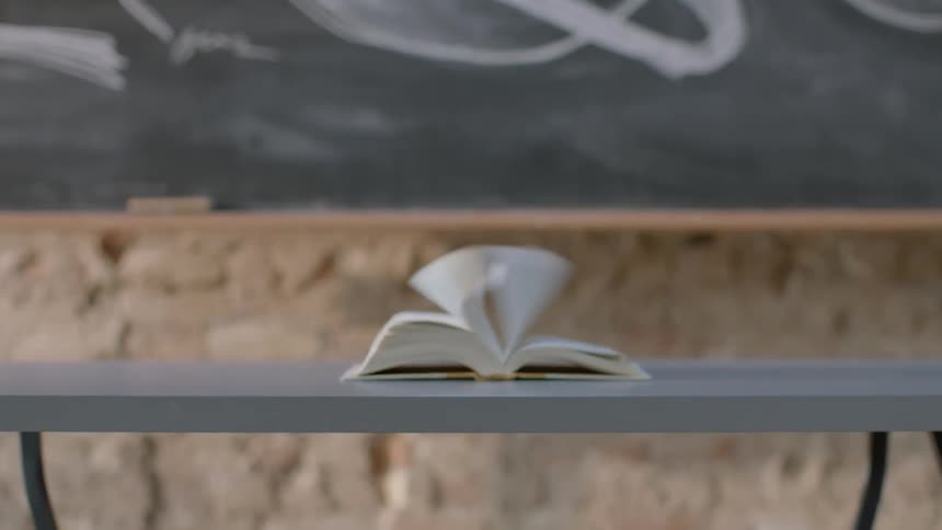 The pages of a book sitting on a table are blown open