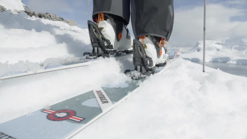 Person snaps their boot into a ski and the top of a hill