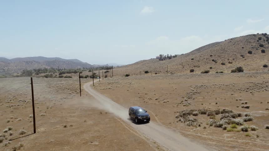 The van rides down the dirt road on a sunny day