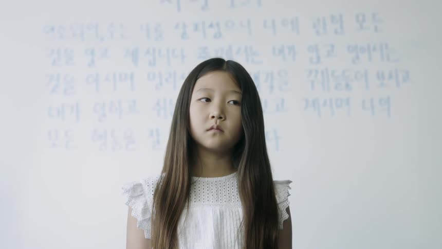 A worried girl stands in front of a white board