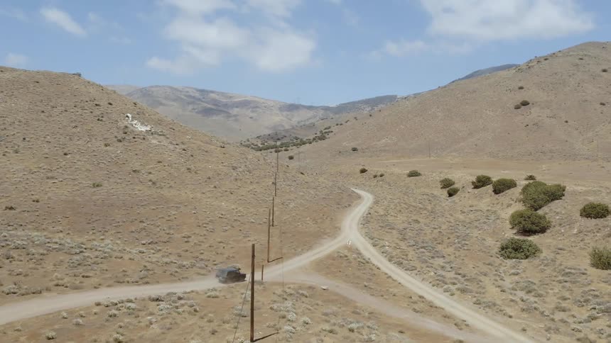 A vehicle drives on a rural dirt road