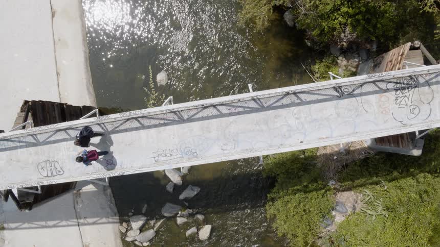 Two people cross the small bridge over the stream